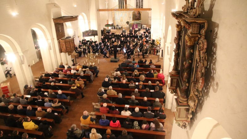 Blick von der Orgel in das Kirchenschiff. Alle Plätze sind belegt. Davor steht das Marinemusikkorps.