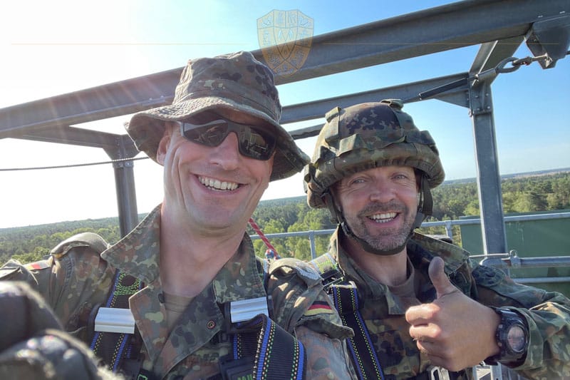 2 Soldaten kurz vor dem Abstieg. Die sonne scheint, beide lachen, einer zeigt den Daumen nach oben