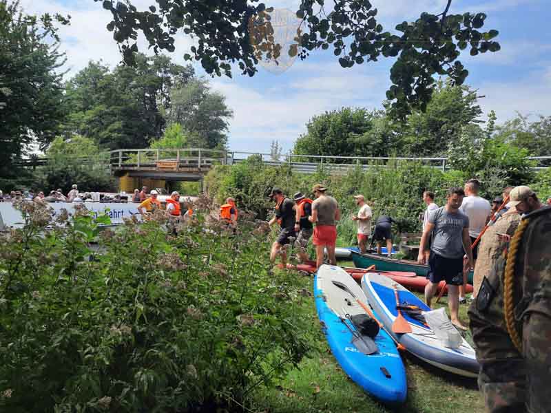 Soldaten mit ihren Wassersportgeräten am Ufer des Dieksee. Im Hintergrund ein Seerundfahrtschiff